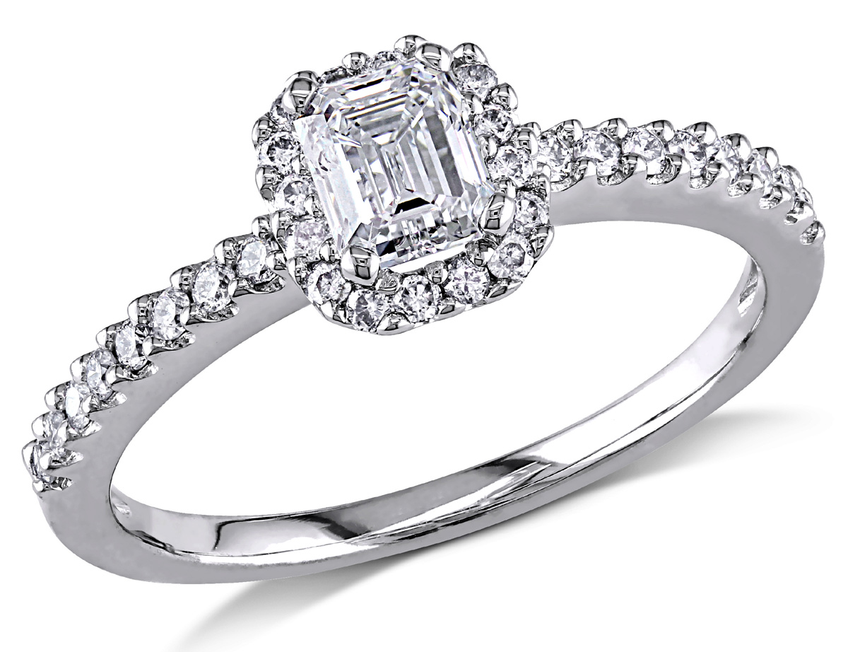 This beautiful ring features an emerald-cut diamond center stone with accenting round diamonds set in 14 karat white gold. The ring glimmers with a highly polished finish.