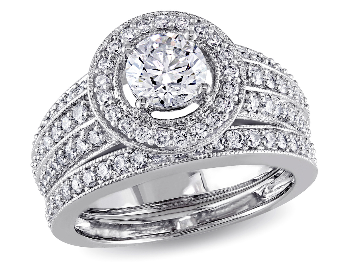 This exquisite one-of-a-kind bridal set features a gorgeous engagement ring with a round-cut white diamond center stone surrounded by a halo of scintillating diamonds. This brilliant ring is complemented by a stunning eternity band. The rings are crafted of gleaming 14-karat white gold enhanced with a miligrain finish.